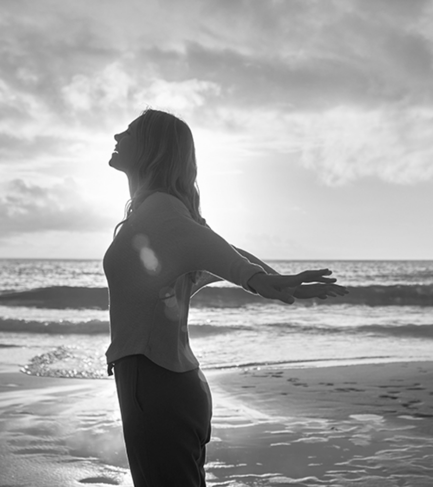 Silhoutte of a Woman with Arms Stretched Out and the Beach in the Background