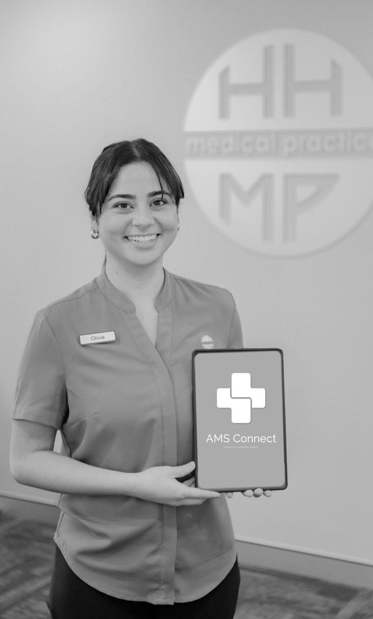 A staff member holding a tablet showing the AMS Connect app in front of the practice logo