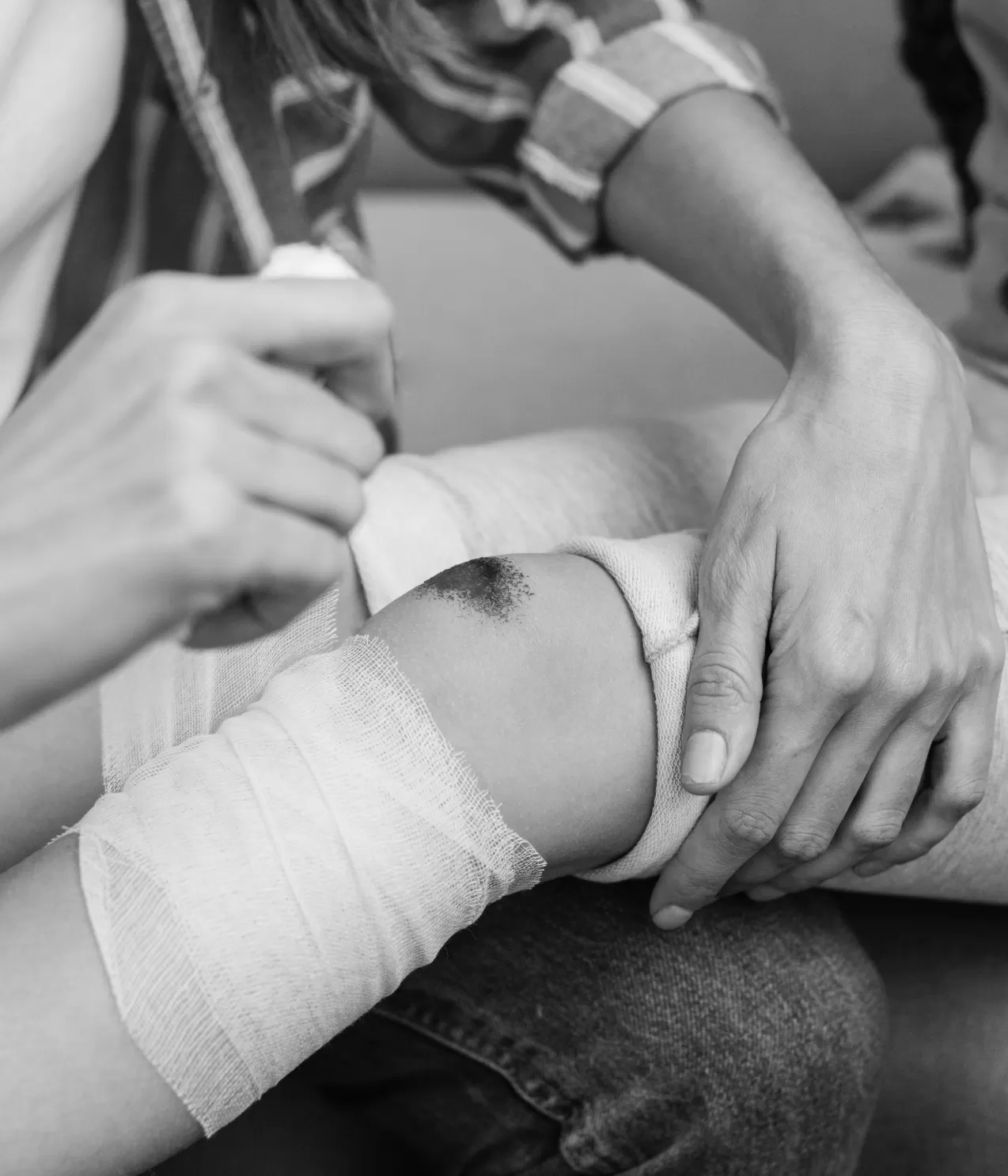 A gloved clinician dressing a wound on a patient's knee