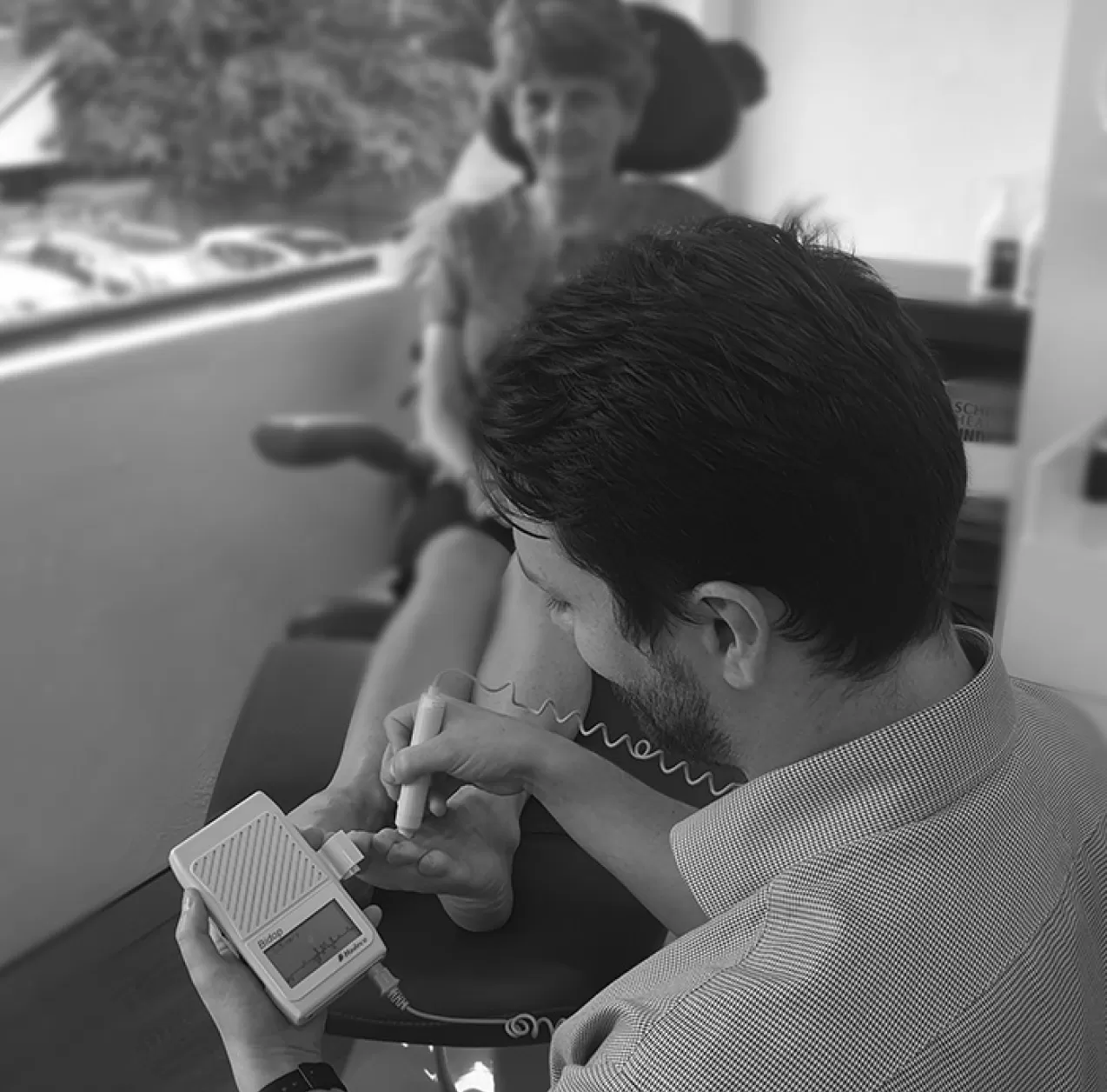 A podiatrist using a hand-held device to treat a patient's foot