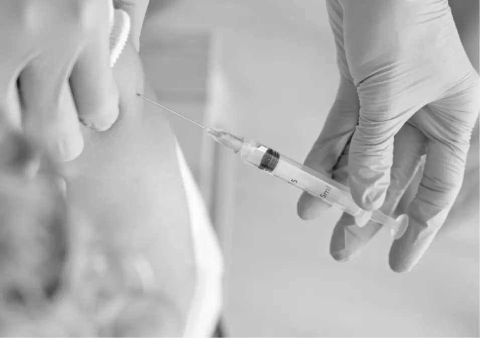 A gloved clinician giving a vaccination in a patient's upper arm