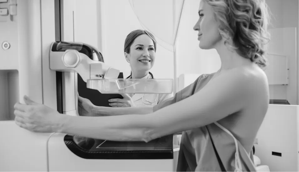 A radiographer positioning a patient for a mammogram