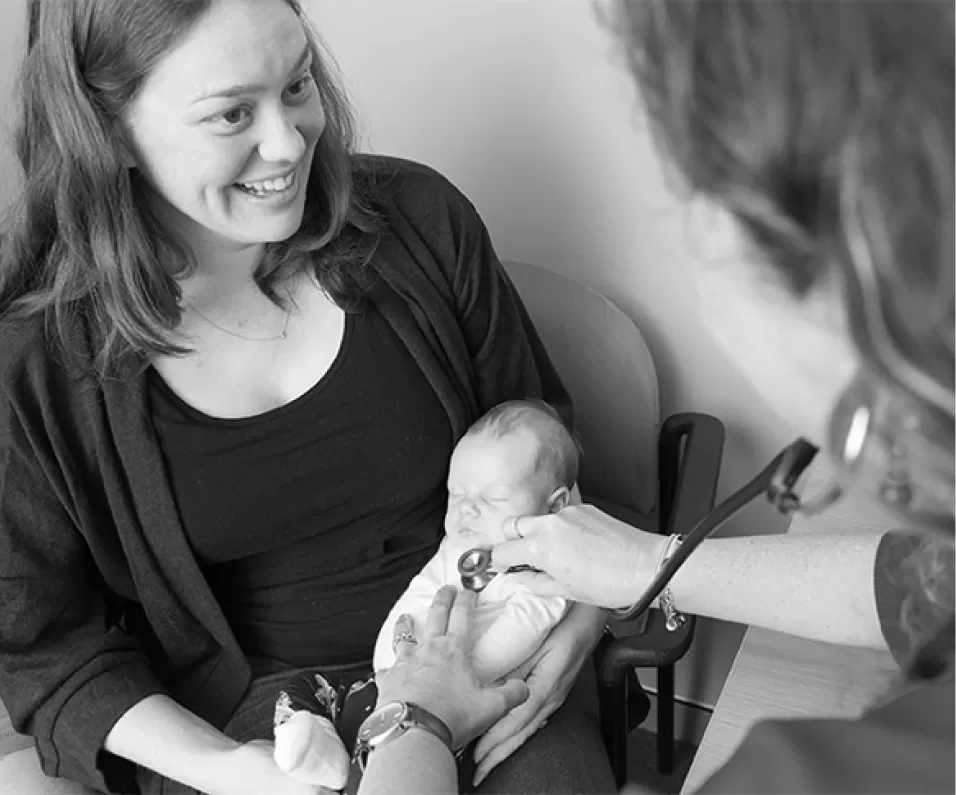 A clinician examining a baby held on a parent's lap