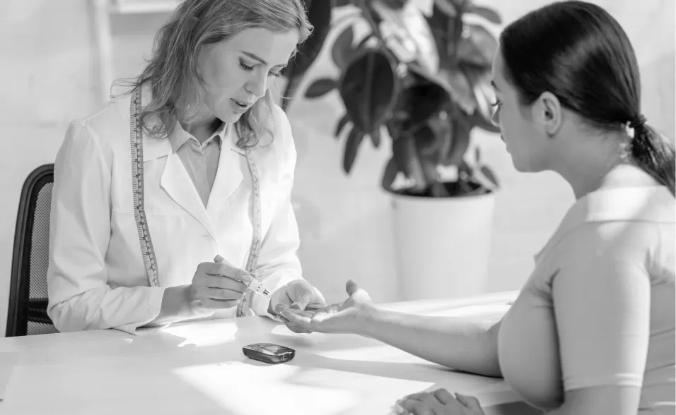 A clinician taking a fingerprick blood glucose reading from a patient