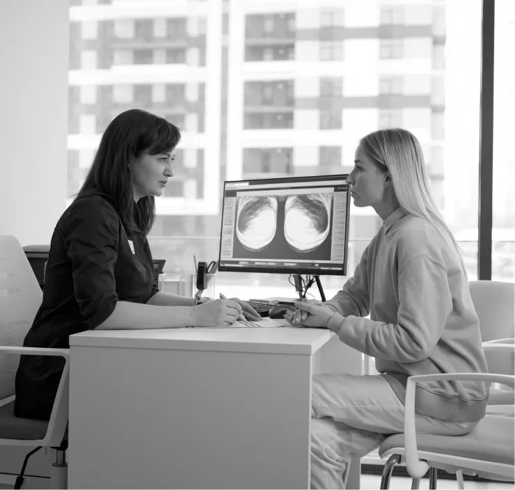 A clinician and a patient reviewing scan images on a screen together