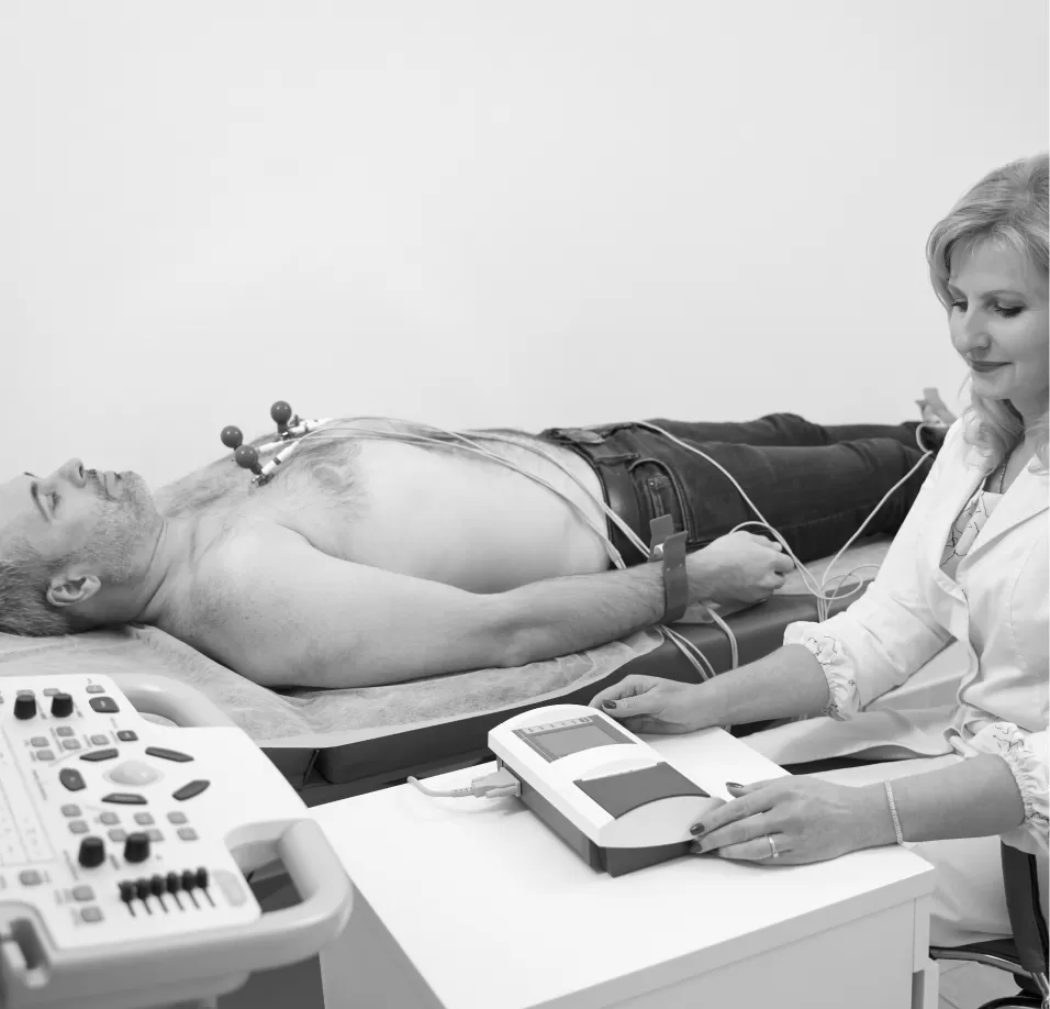 A patient lying down connected to an ECG machine while a clinician records the trace