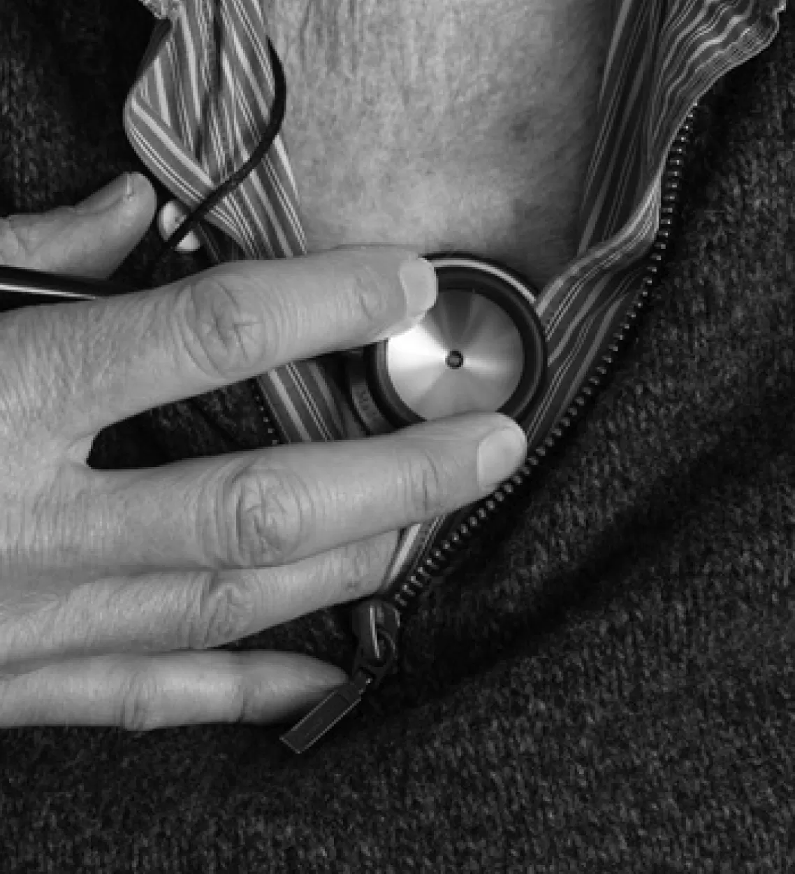 A clinician listening to an older patient's chest with a stethoscope