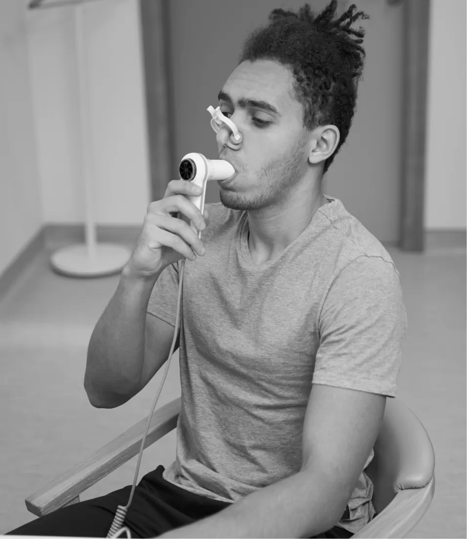 A young man blowing into a hand-held spirometer