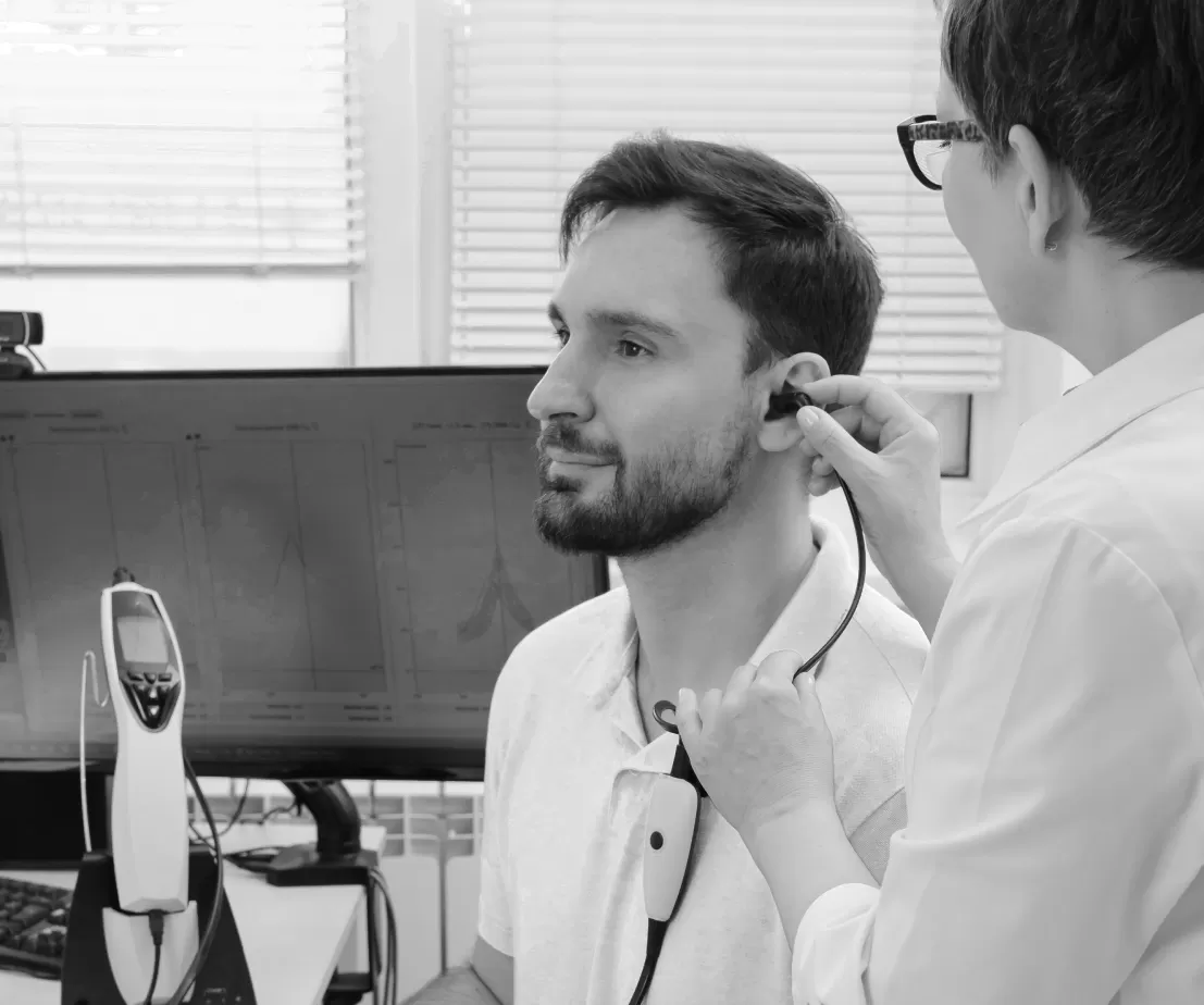 An audiologist fitting a hearing device to a patient's ear