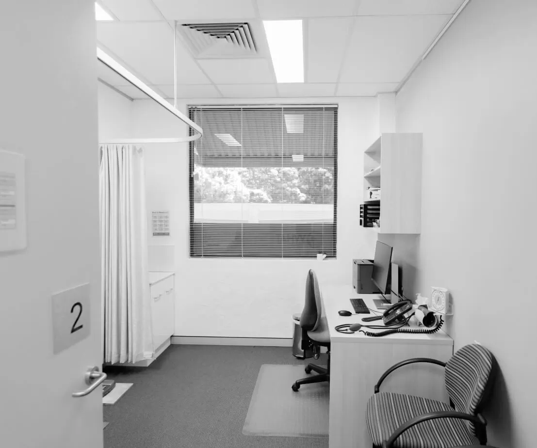 A sessional specialist consulting room with an examination bed, desk and privacy curtain