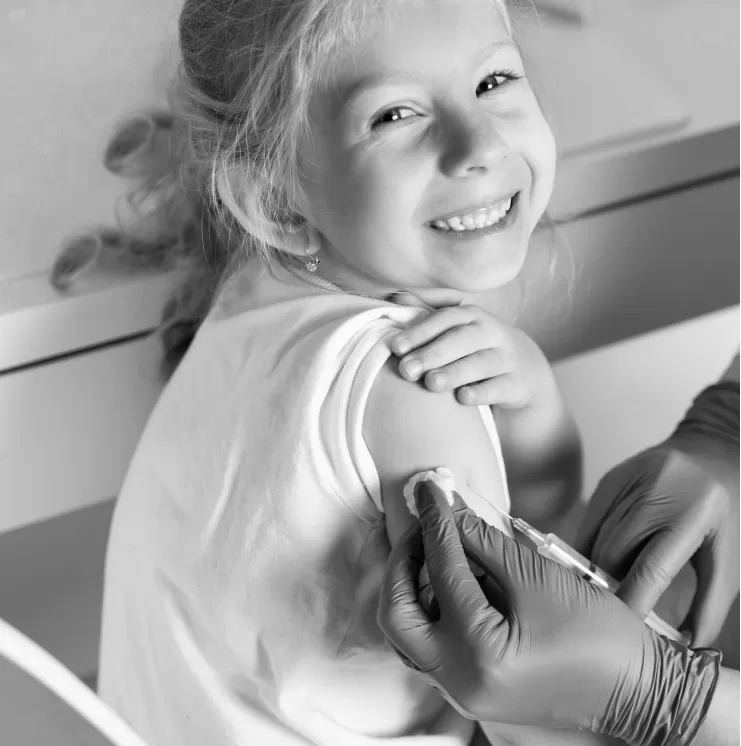 A young girl smiling as she receives a vaccination in her upper arm