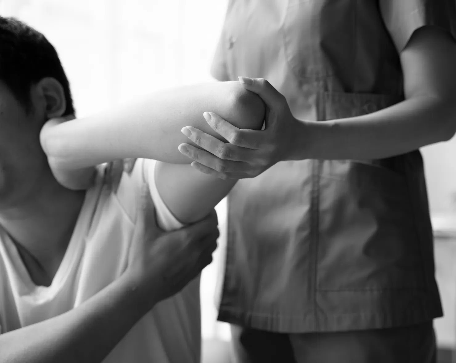 A physiotherapist supporting a patient's arm and shoulder during treatment