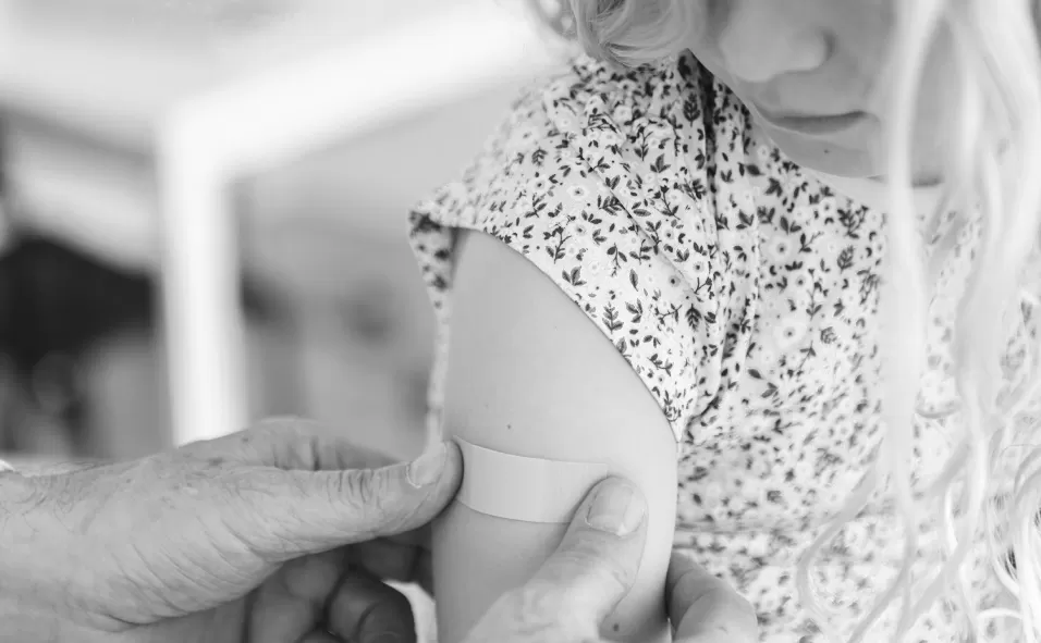 A clinician applying a plaster to a child's upper arm after a vaccination