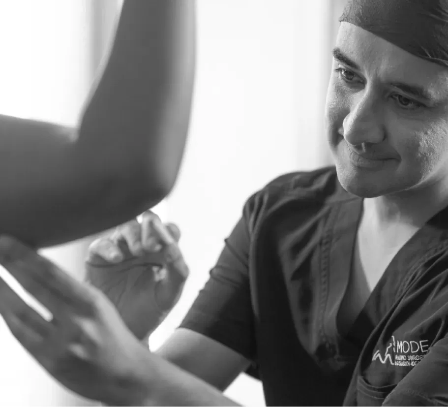 A surgeon in scrubs treating a patient's arm