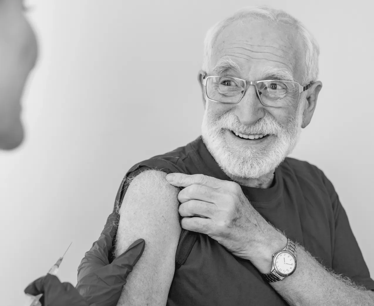 An older man holding up his sleeve after a vaccination in his upper arm