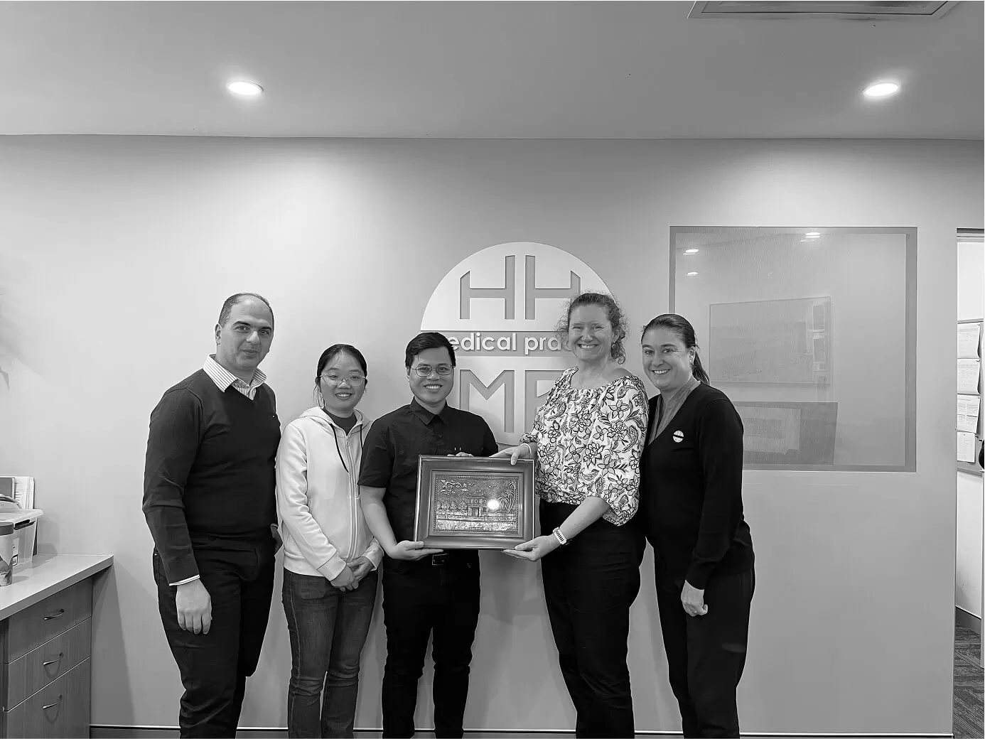 Workshop participants with a certificate in front of the practice logo