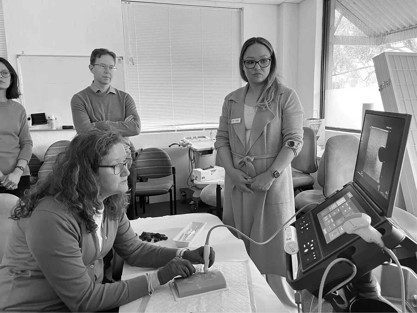 Trainees observing a clinician at a workstation during a teaching session