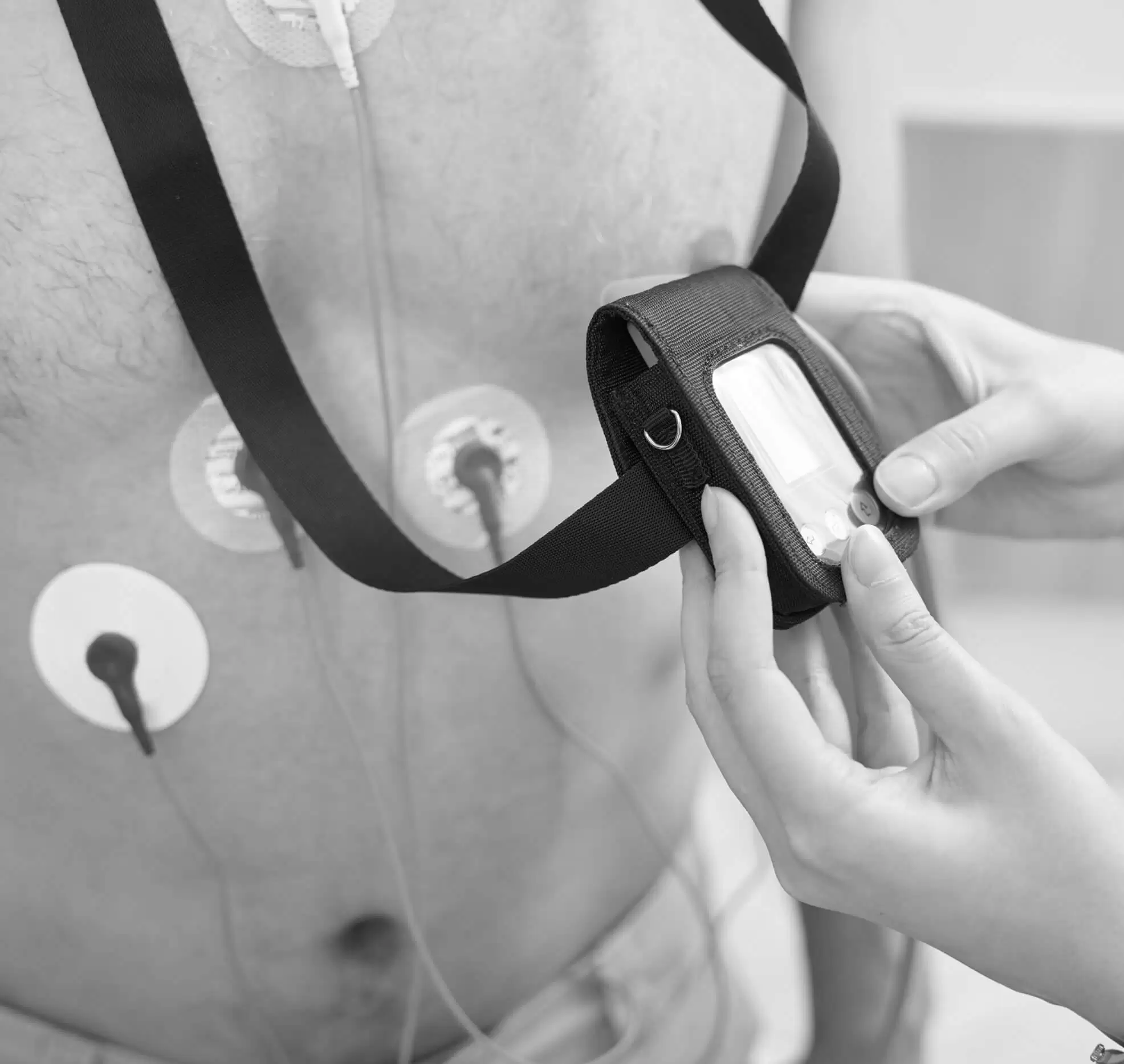A clinician fitting a Holter monitor to a patient's chest