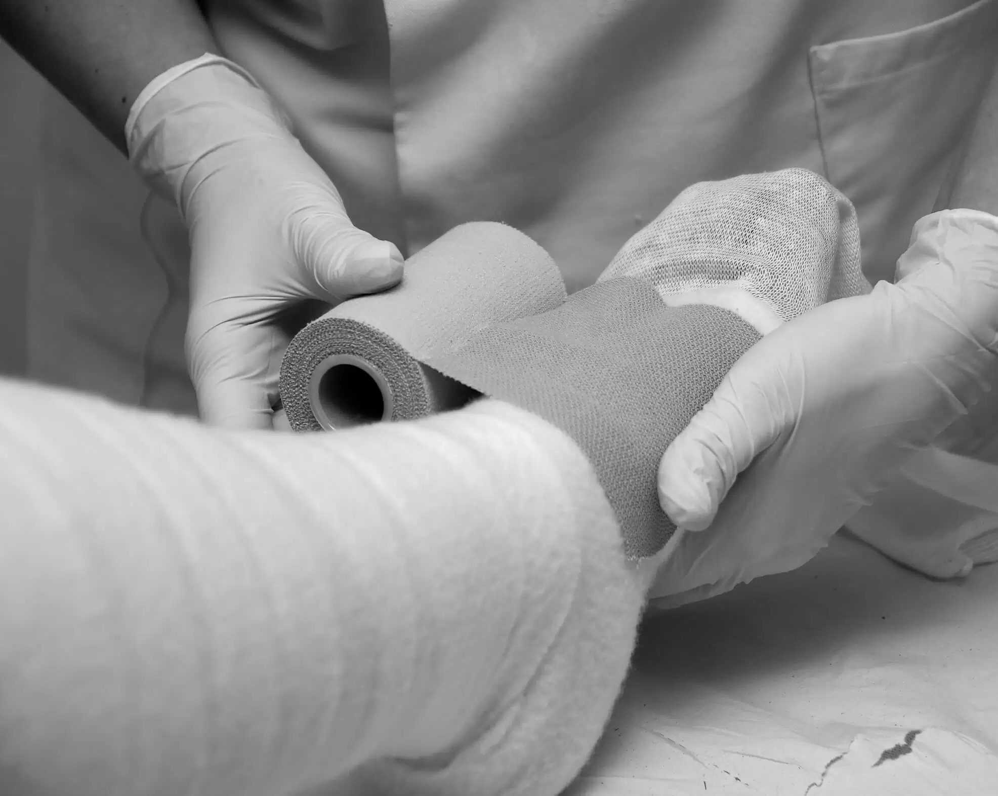 A gloved clinician applying a bandage to a patient's arm