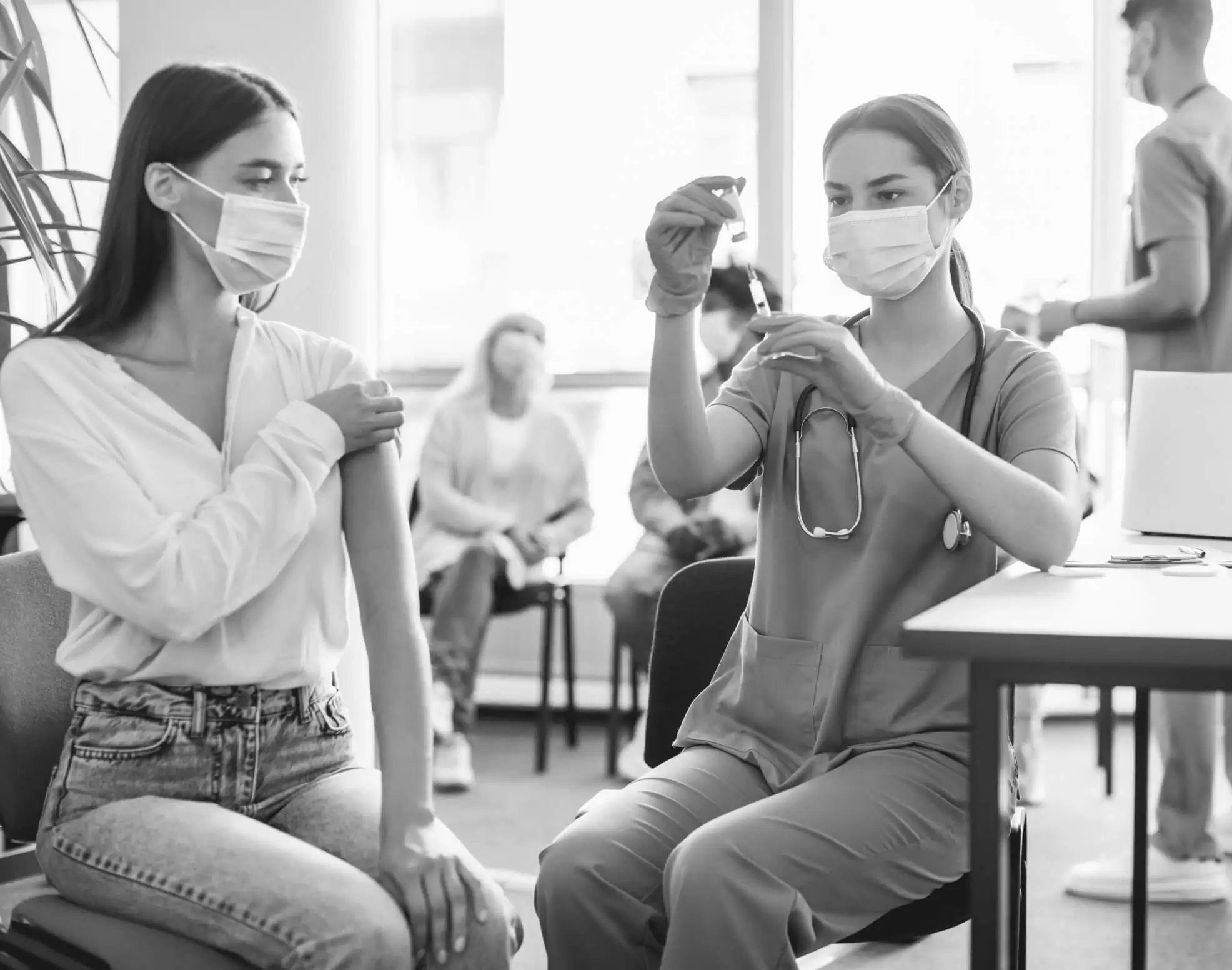 A clinician giving a patient an injection in the upper arm at a clinic