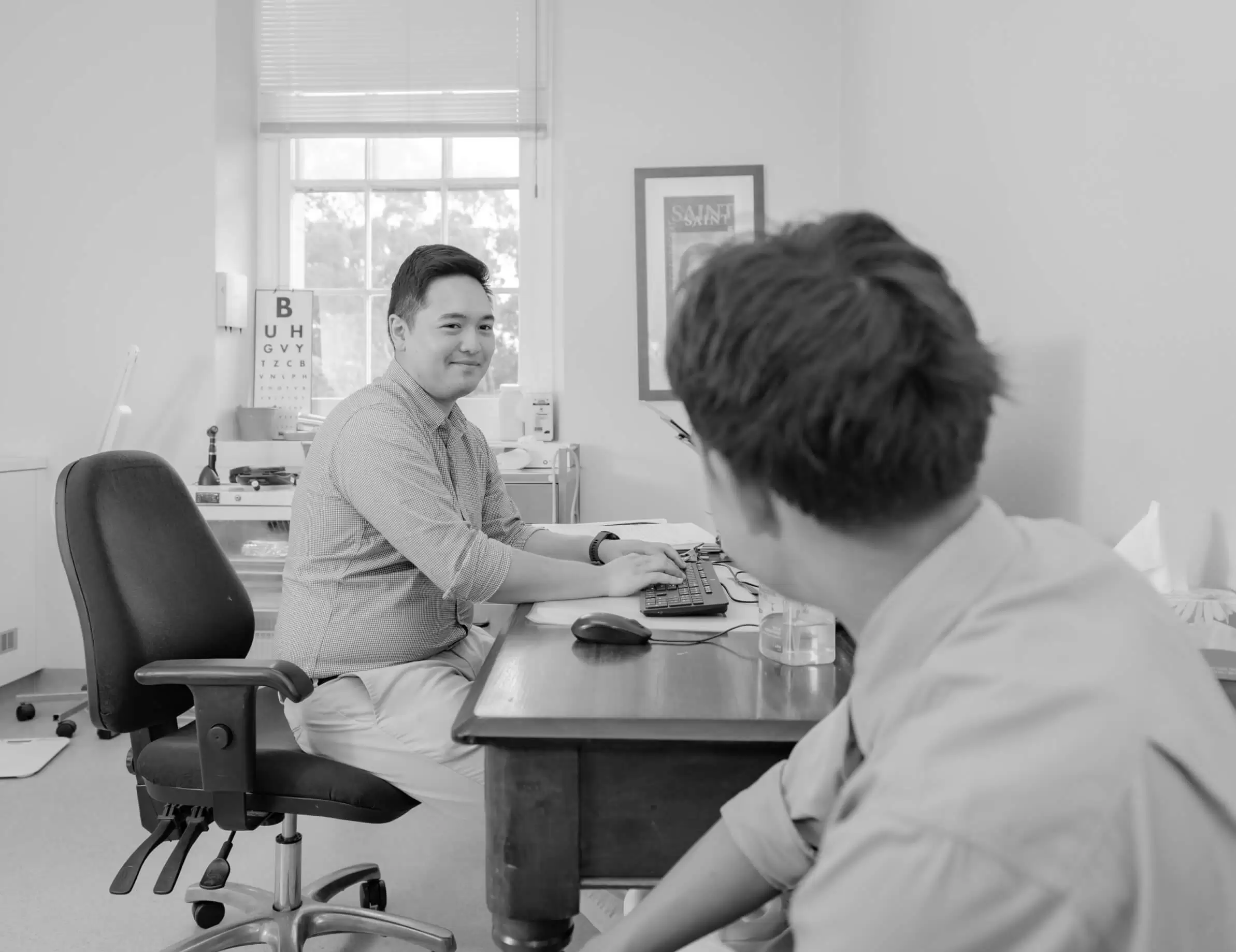 A doctor talking with a patient across the desk in a consulting room