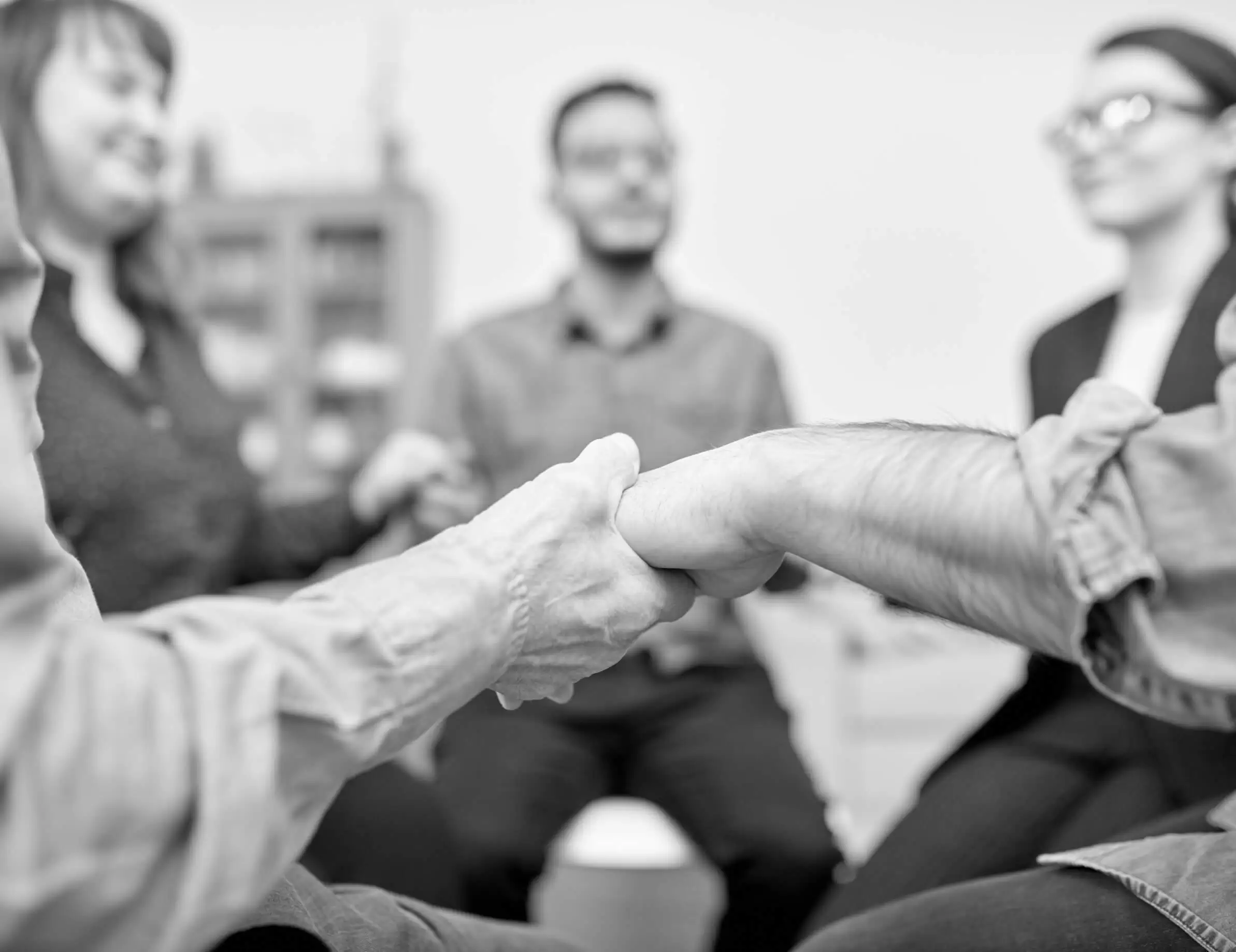 People in a group session reaching out to hold hands