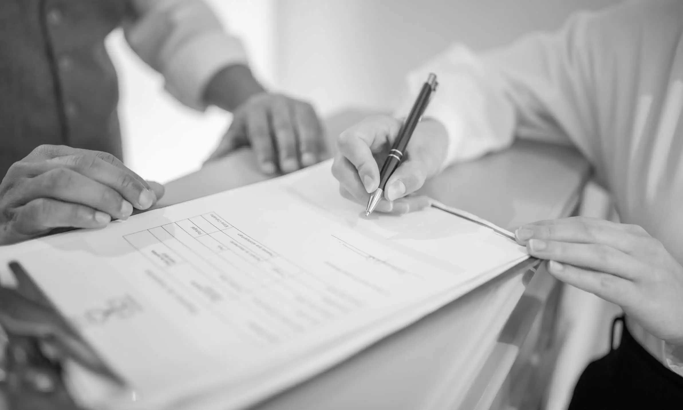 A patient completing a paper form while a clinician looks on