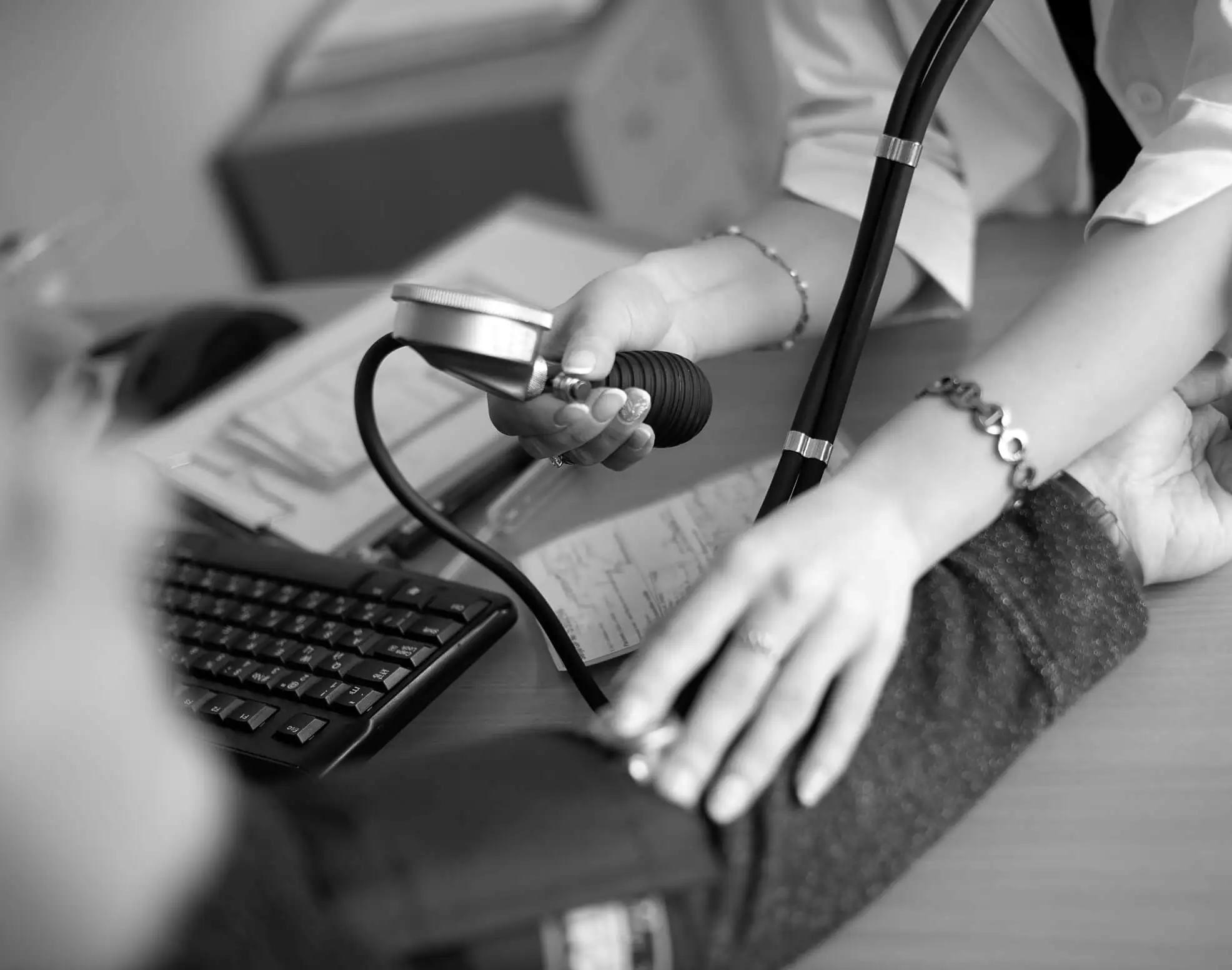 A clinician taking a patient's blood pressure at a desk