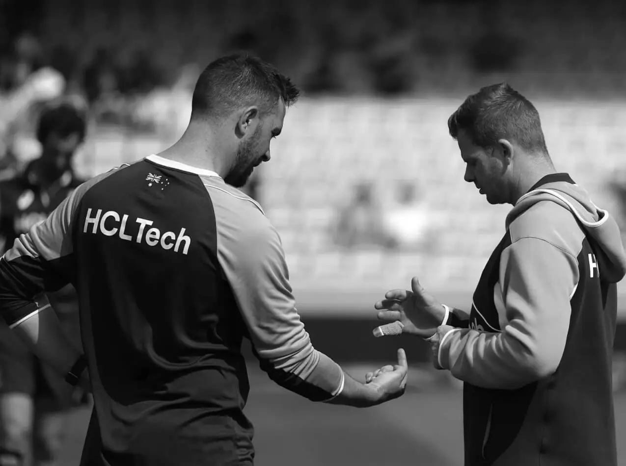 A sports medicine clinician assessing a player's hand at the side of the pitch