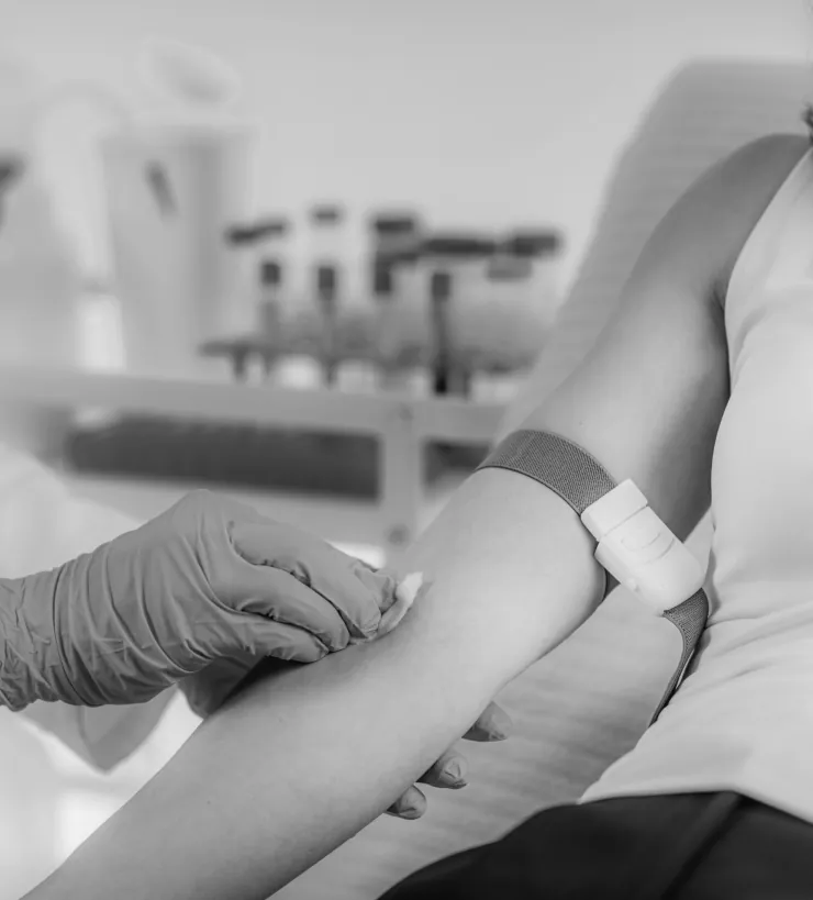 A gloved phlebotomist taking a blood sample from a patient's arm