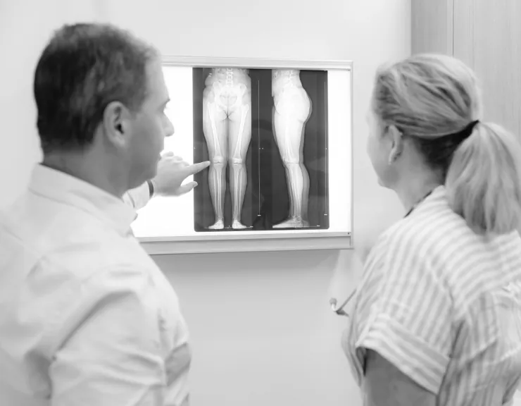 A doctor discussing a leg X-ray with a patient at a light box